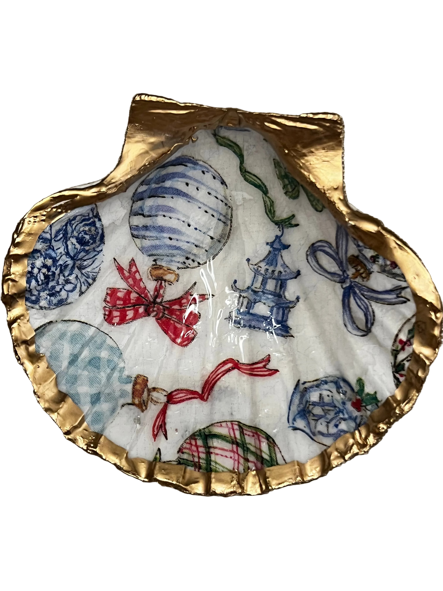 A decorative trinket shell with blue and white chinoiserie images, sealed in resin and trimmed in gold leaf.
