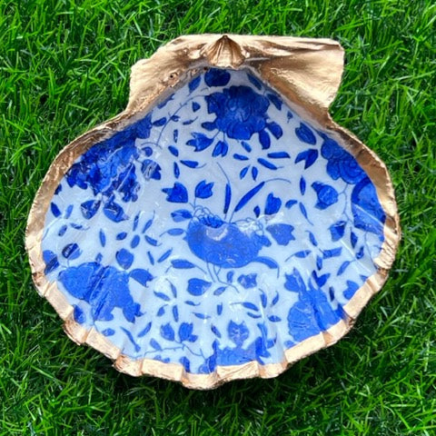 A cobalt blue floral patterned trinket shell with gold leaf trim, displayed on a green background.
